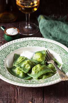 Green Spinach Ravioli with Cream Sauce and White Wine on Rustic Table, Italian Cuisine.