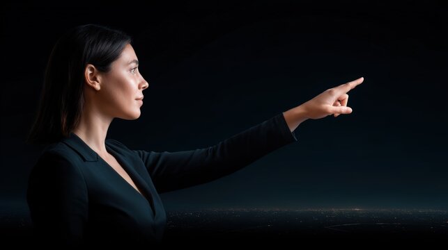 A focused woman in a dark outfit points forward against a dark background, suggesting interaction with a virtual or futuristic interface.