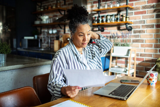 Senior woman reviewing bills at home kitchen