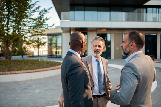 Three business executives discussing strategy outside office building