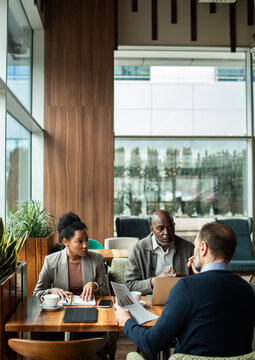 Three business colleagues discussing report in modern cafe