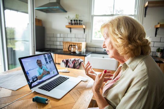Senior woman consulting doctor via telemedicine in home kitchen