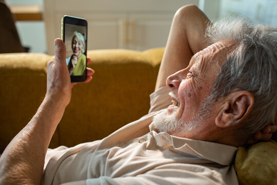 Elderly man making a video call from the sofa at home