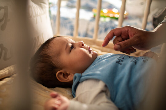 Parent soothing infant in crib at home