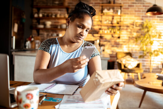 Woman scanning package with smartphone at home