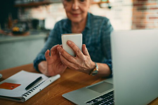 Senior woman using smartphone for online banking at home