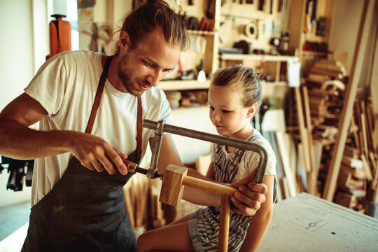 Man teaching girl woodworking in home workshop