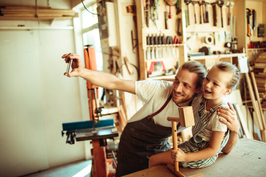 Man and girl taking selfie in carpentry workshop