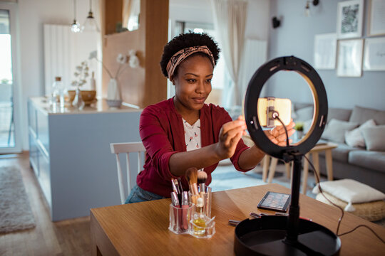Young woman filming makeup tutorial at home