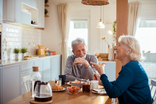 Senior couple enjoying breakfast together in home kitchen
