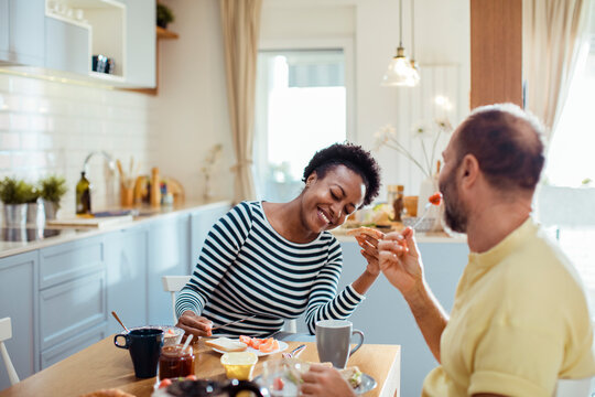Happy couple enjoying breakfast together in a home kitchen