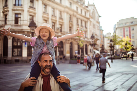 Father carrying daughter on shoulders in sunny european city