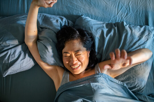 Smiling woman stretching in bed at home
