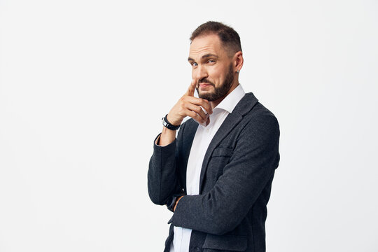 Professional man in a smart casual jacket and white shirt stands against an isolated white background, projecting confidence, focus, and calm leadership in a thoughtful pose.