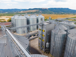 Storage facility for grains located in a rural area with silos and machinery visible under a cloudy sky © DSMT