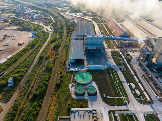 Obraz premium Factory site with large buildings, industrial equipment, and green tanks showing process and activity during daytime hours