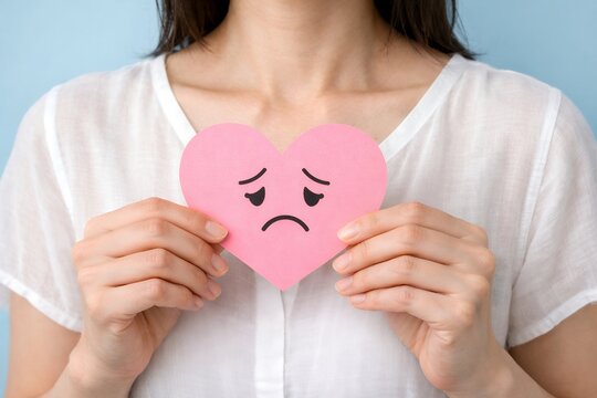 悲しい顔のピンクハートを胸元に抱え心の不安を表現する女性