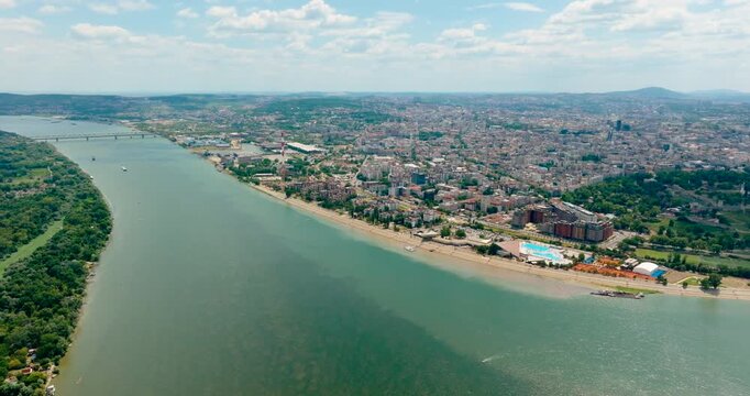 Drone panning shot over the riverside area of Belgrade, Serbia, featuring beaches, parks and the opposite bank with the city skyline along the Danube and Sava rivers in summer before Expo 2027.