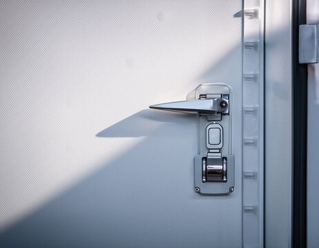 clean refrigerated container door with metal lock silver handle cold air white panel side light soft shadow copy space