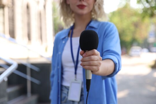 Professional journalist with microphone working outdoors, closeup