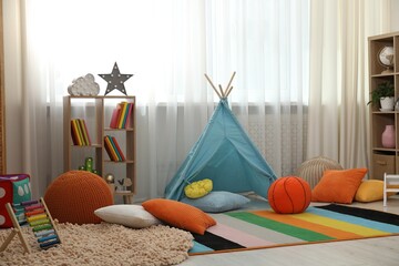 Blue wigwam, colorful pillows, poufs and shelving unit in stylish child's room. Interior design © New Africa