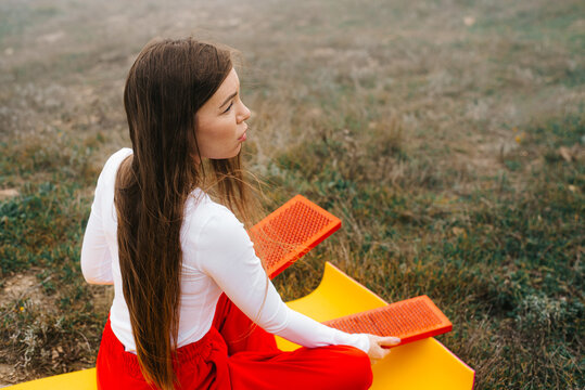 Thoughtful woman holding sadhu nail boards resting on a yoga mat