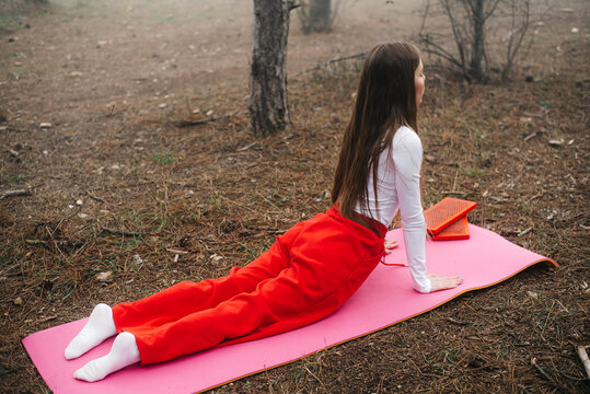 Back view of a woman stretching in yoga cobra pose outdoors