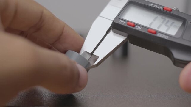 Engineer measuring small part with digital caliper