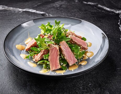tuna salad with dressing and greens sat on a stony surface