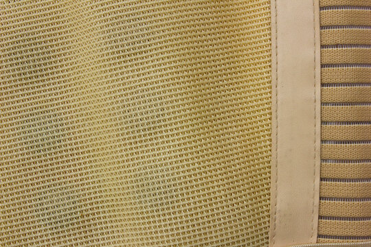 A background and lined texture captured from a close-up horizontal photo of a light brown flexible woven fabric.