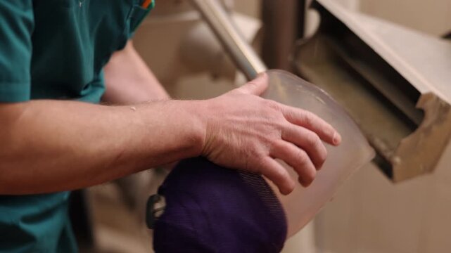 prosthetic socket, socket shaping, manual grinding. Close-up of technician's hands refining clear prosthetic socket on industrial grinder as part of custom limb preparation