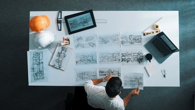 Top down aerial view of architect engineer placing building blueprint on table while checking and choosing project plan. Interior designer select architectural plan from meeting table. Alimentation.