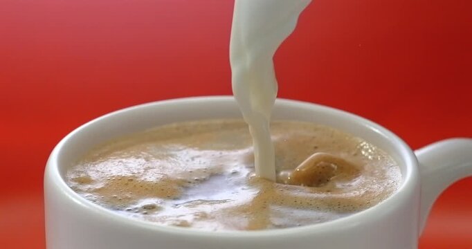 Cream pouring into coffee red background super slow motion