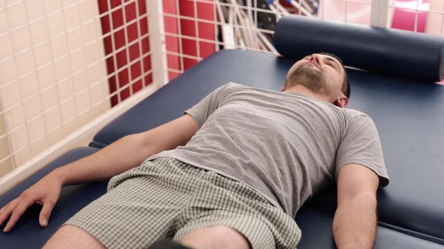 amputee rehabilitation, functional training, therapeutic exercise. Male amputee completing straight leg raise exercise on rehabilitation table as part physiotherapy session in medical clinic.