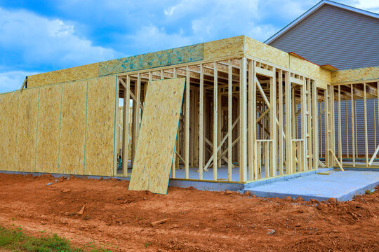 Workers are framing new home in neighborhood with wooden boards construction progress.