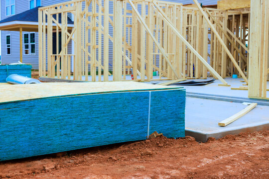 Wooden beams frames stand at construction site where new house is being built construction materials are arranged nearby.