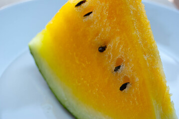 Close-up picture of a yellow watermelon showing its juicy flesh, fresh texture, and vibrant summer color. © Amina
