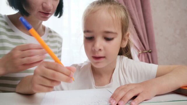 Focused child studying at home with mother support learning concept