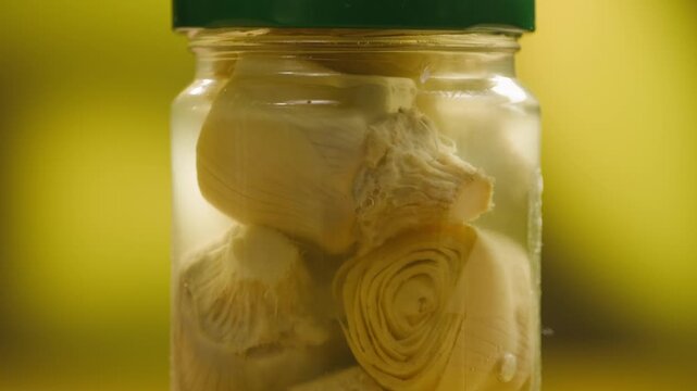 Marinated artichokes in a glass jar isolated on a white background. Mediterranean preserved vegetables, gourmet appetizer, healthy organic food, ready to eat, close-up.