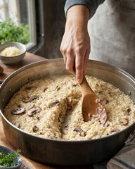 Fototapeta premium Cooking creamy mushroom risotto in a large pan with a wooden spoon
