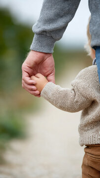 Caucasian adult and child holding hands on outdoor pathway