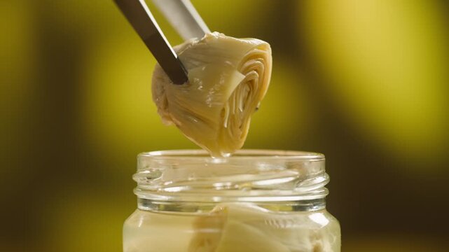 Marinated artichokes in a glass jar isolated on a white background. Mediterranean preserved vegetables, gourmet appetizer, healthy organic food, ready to eat, close-up.