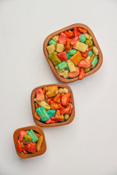 Colourful prawn crackers in wooden bowls on a white background, flat lay