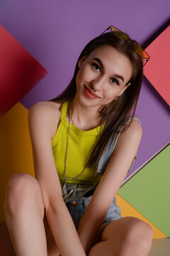 Young woman in yellow top sitting against colorful geometric background