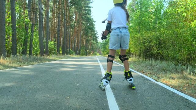 Girl is roller skating by forest, enjoying an active hobby in the open air.