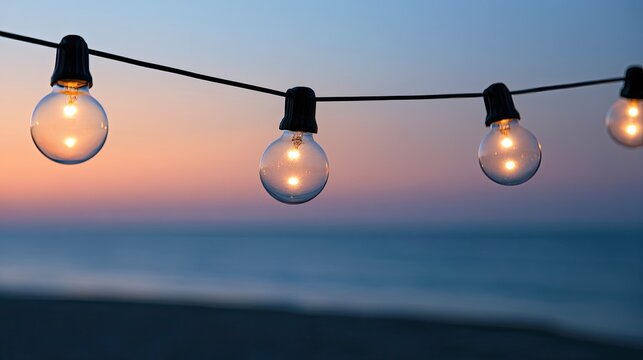Outdoor string lights glow against a twilight sky and ocean