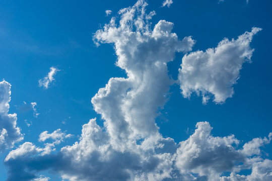 Towering white cumulus cloud rising in deep blue summer sky