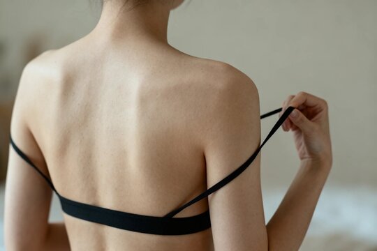 Woman Adjusting Bra Strap on Her Back