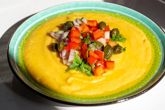 Side angle view of Greek fava split pea dip garnished with capers diced tomatoes and chopped onion