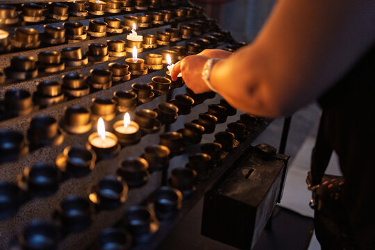 Person lighting votive candles for prayer and hope